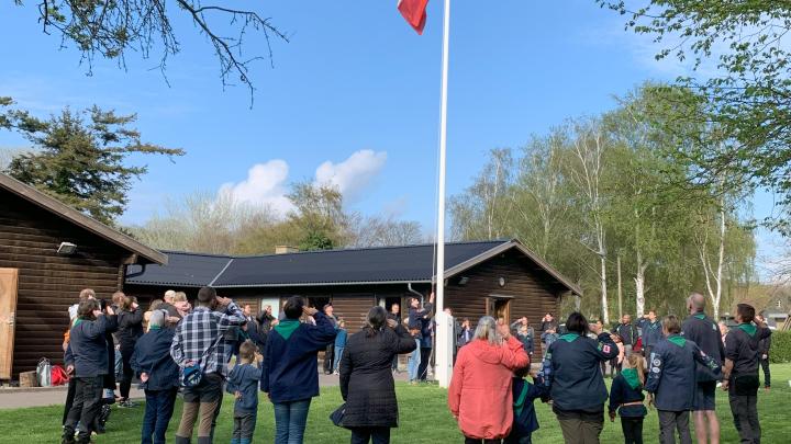 Spejdere og forældre hejser flag ved spejderhytten